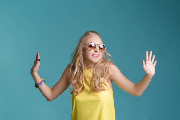 portrait of beautiful blond woman in sunglasses and yellow shirt on blue background. Carefree summer. - Fotoğraf, Görsel