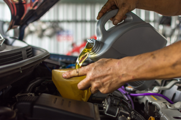 Mecánico de coche llena un lubricante fresco aceite de motor
 - Foto, imagen