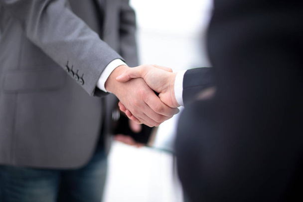 Dos hombres de negocios seguros estrechando la mano durante una reunión en la oficina, el éxito, el trato, el saludo y el concepto de socio
. - Foto, Imagen