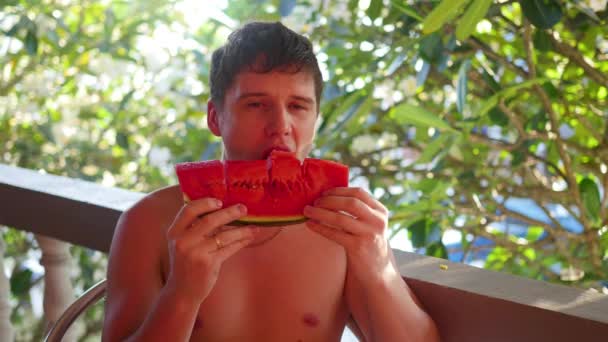 Ο τύπος τρώει ένα γλυκό ζουμερό καρπούζι σε μια καυτή καλοκαιρινή μέρα - Πλάνα, βίντεο