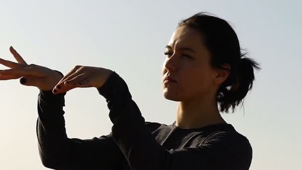 Mädchen bei Sonnenuntergang macht Bewegung für gesunde Handgelenke. - Filmmaterial, Video