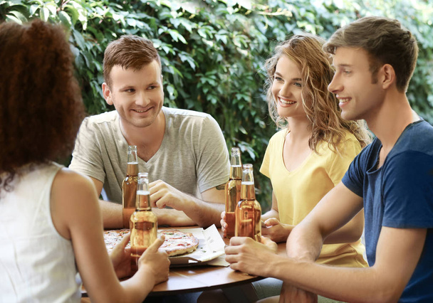 Vrienden zitten in café met vers bier en lekkere pizza - Foto, afbeelding