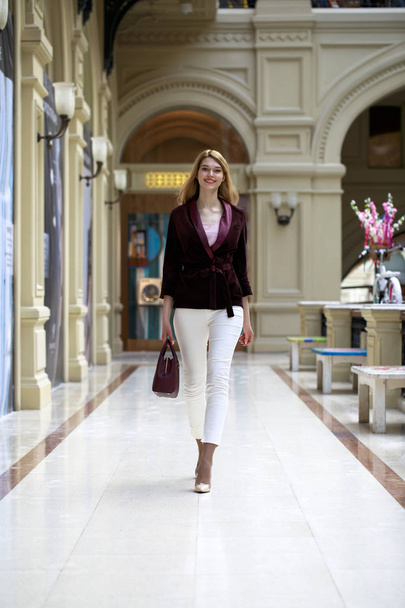 Beautiful blonde woman in white pants and corduroy jacket  - Фото, изображение
