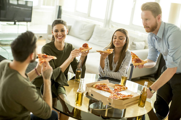 Amigos comiendo pizza en el interior moderno
 - Foto, Imagen