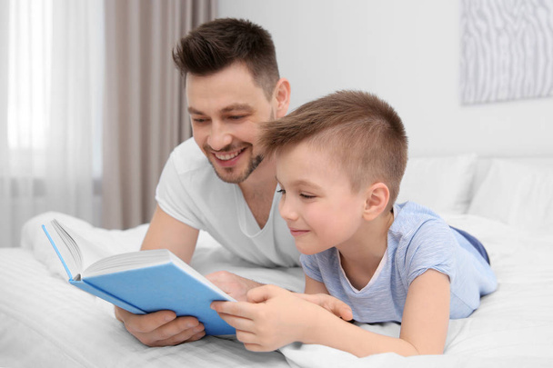 Dad and son reading interesting book   - Фото, зображення