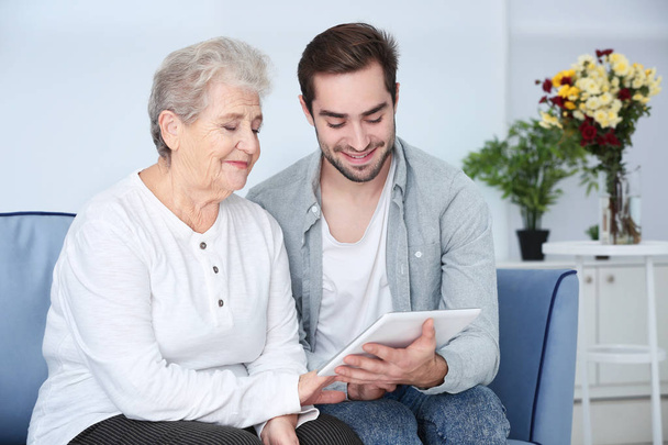 Grandmother and grandson using tablet on sofa at home - Foto, Imagem