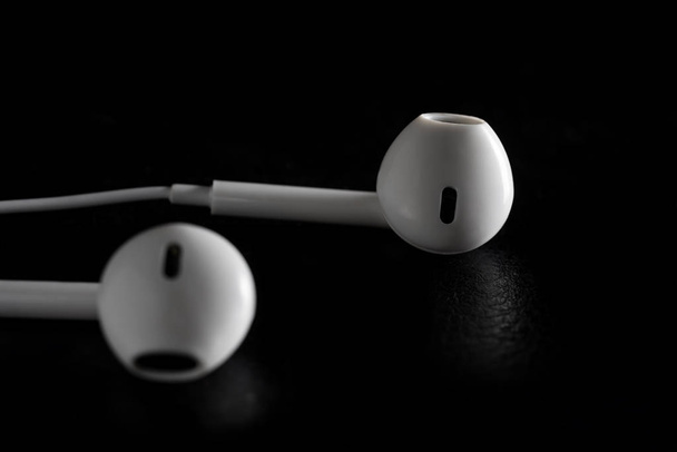 Auriculares para el oído sobre fondo negro
 - Foto, Imagen