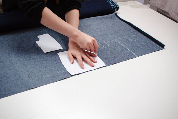 Seamstress hands on the work table with pattern and measuring tape. - Фото, изображение