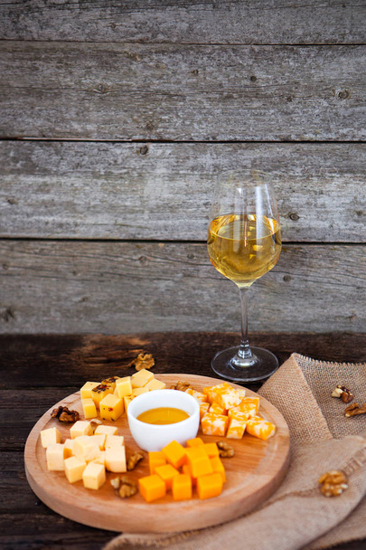 Σταφυλιών, τυρί, σύκα και μέλι με ένα ποτήρι λευκό κρασί στο woo - Φωτογραφία, εικόνα