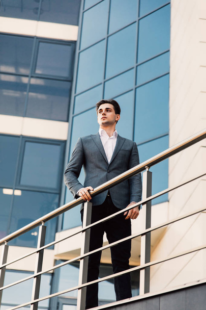 Handsome young business man at balcony of office building outdoors looking forward - Photo, Image