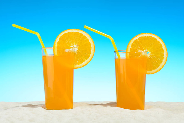 Dos vasos de jugo de naranja en la playa
 - Foto, imagen