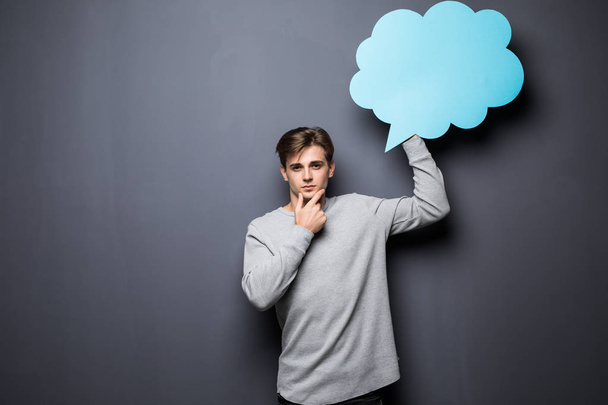 Man with hands on chin holding blue blank speech bubble with space for text on grey background - Foto, immagini