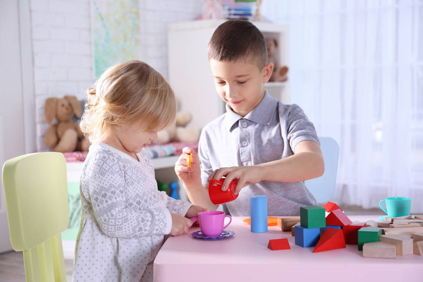 Cute little sister and brother playing with toy blocks at home - Foto, imagen