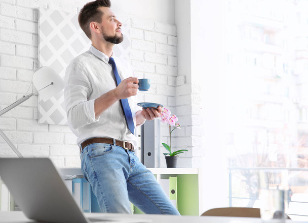 young man drinking coffee in office - Foto, Imagen