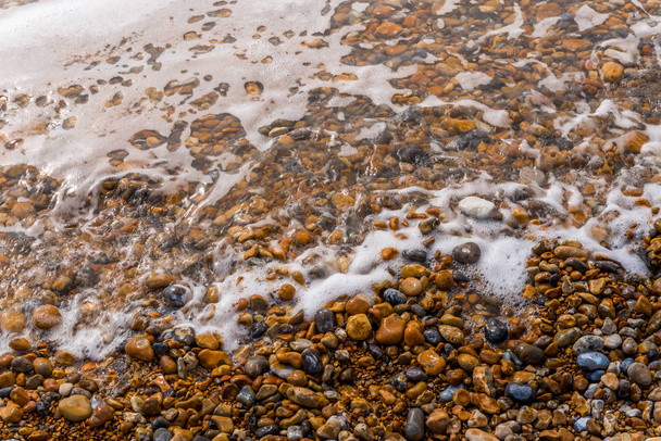 Το Top view στην παραλία με χαλίκι, όμορφες χρωματιστές πέτρες, πλένονται με  - Φωτογραφία, εικόνα