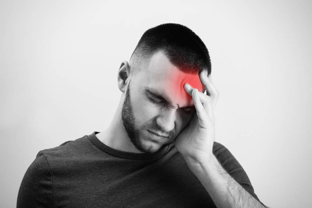 Young man suffering from headache on light background - Foto, Bild