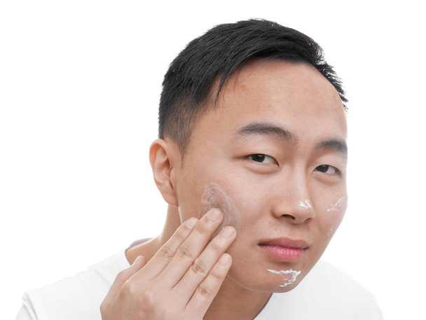 Young Asian man applying cream  - Фото, изображение