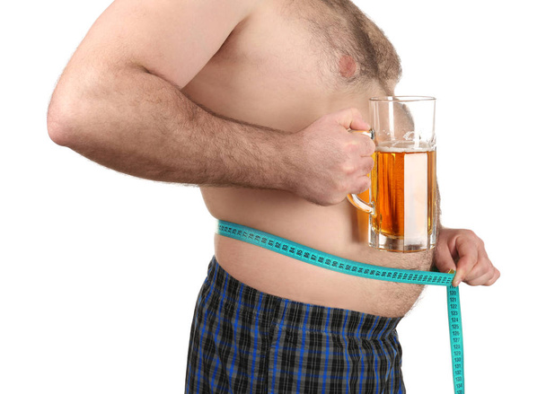Man measuring belly and holding glass of beer on white background - Foto, imagen