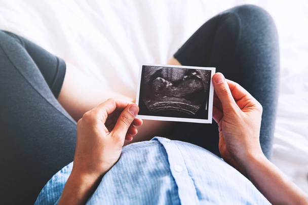Pregnant woman holding ultrasound image - Фото, зображення