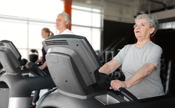 Senior woman running on treadmill in gym - Foto, Imagem