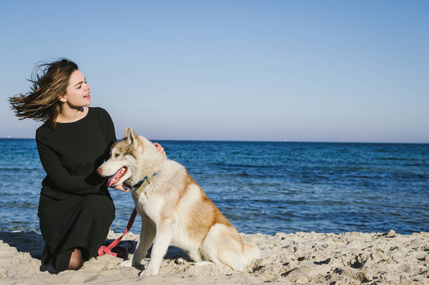 Woman on sea beach with siberian husky dog - Фото, изображение