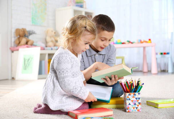 Cute little brother and sister sitting on floor with colorful notebooks - Φωτογραφία, εικόνα