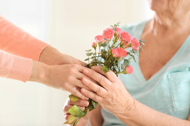 giving flowers to old woman - Foto, Imagem