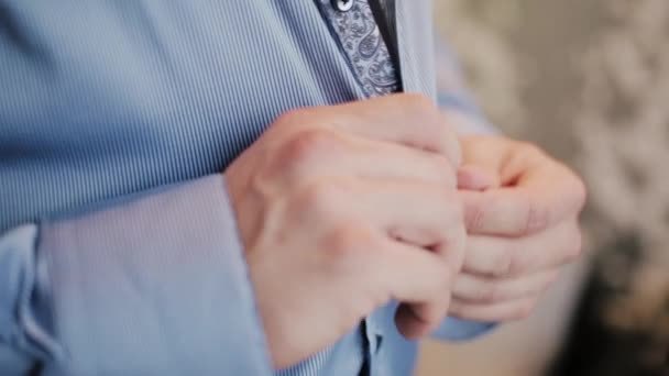Close-up view of male hands buttons a shirt. Man getting ready for a job, putting his suit on. - Кадри, відео