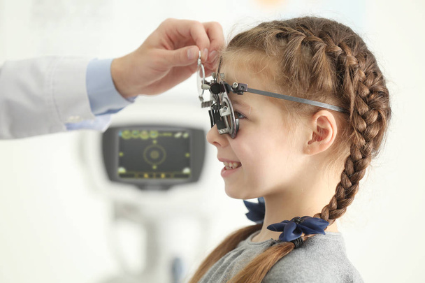 Ophthalmologist examining eyes of little girl in clinic - Foto, afbeelding