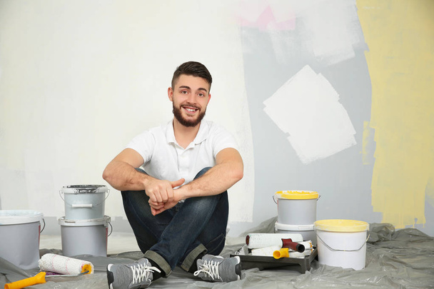 Young male worker with tools sitting on floor - Foto, imagen