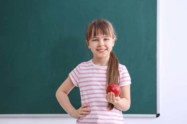 Happy schoolgirl sitting with apple   - Foto, afbeelding
