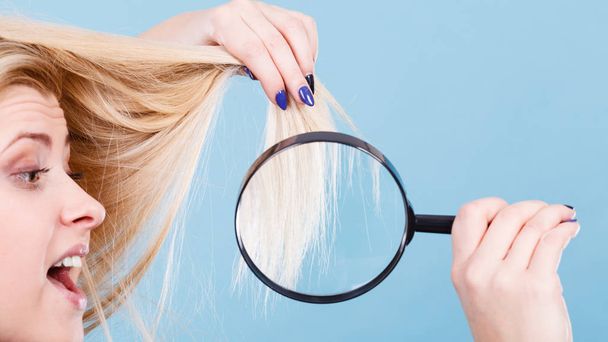 Woman looking at hair through magnifying glass - Foto, Imagem