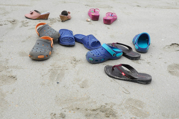 Paires de chaussons pour enfants sur une plage de sable fin
. - Photo, image
