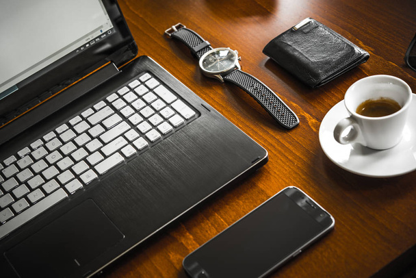 Ordenador portátil, café, reloj, vasos y billetera en escritorio de madera
 - Foto, Imagen
