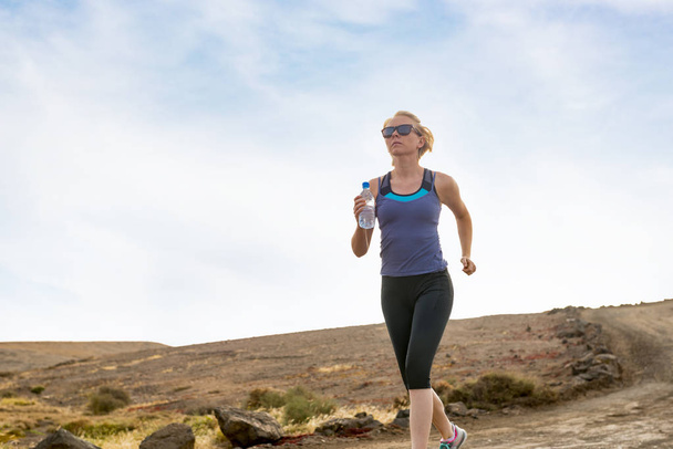Fit Lady avec bouteille d'eau Jogging sur la route de la saleté
 - Photo, image