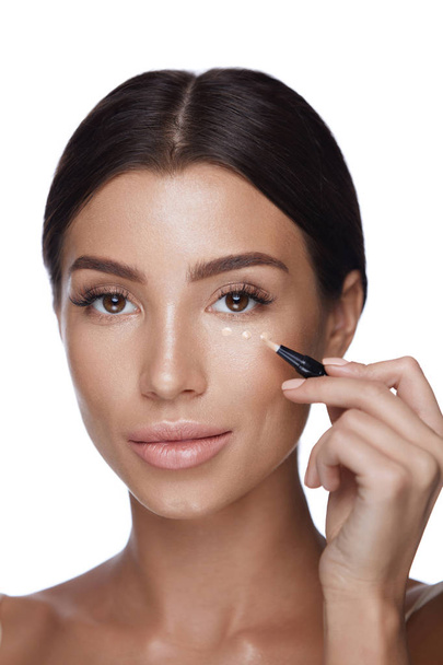 Cosmetics. Beautiful Woman Applying Concealer On Skin Under Eyes - Foto, Imagen