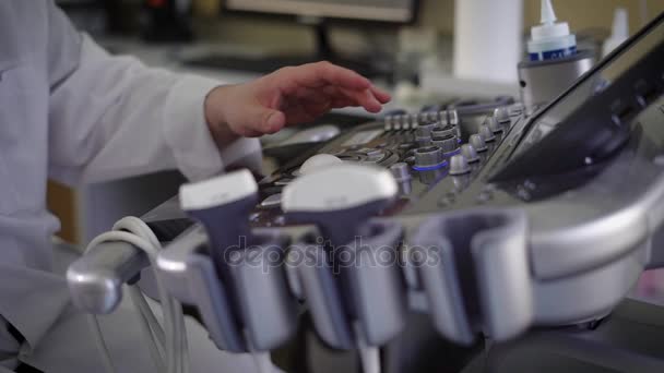 Close-up da placa de controle do dispositivo de diagnóstico de ultra-som no hospital e mão masculina de um médico de casaco branco usando equipamentos médicos e colocando botões difentes
. - Filmagem, Vídeo