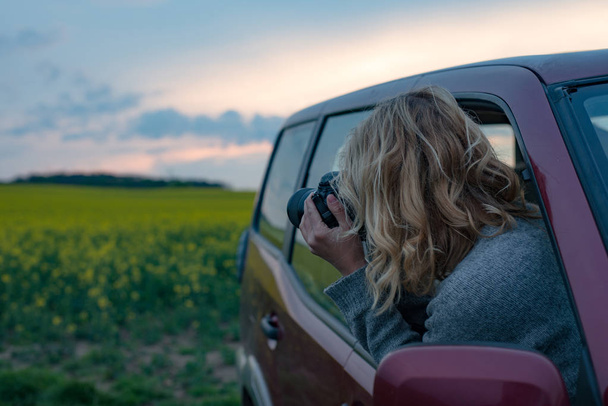 Φωτογράφος γυναίκα λαμβάνοντας εικόνα σε οδικό ταξίδι στο ηλιοβασίλεμα. Κάνοντας ταξιδιωτικό ιστολόγιο. - Φωτογραφία, εικόνα