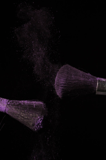 Make up brush with purple dust on black background - Foto, imagen