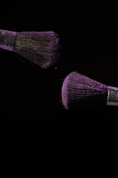 Brosse de maquillage avec poussière violette sur fond noir
 - Photo, image