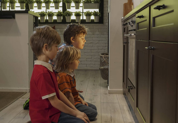 niños sentados cerca del horno en la cocina
 - Foto, imagen