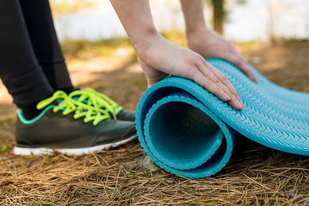 Chica en zapatos deportivos se extiende karemat azul en la naturaleza, para el yoga, w
 - Foto, Imagen