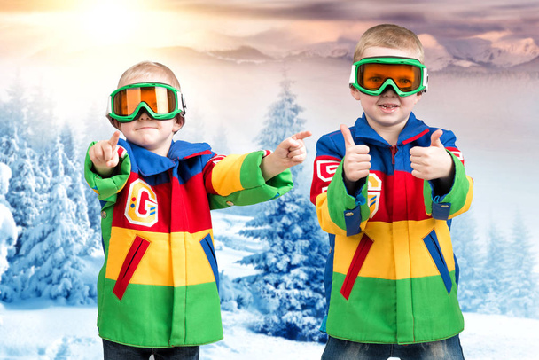 Two brothers of the boy snowboarder in bright ski jackets and goggles is skiing in the mountains. - Foto, imagen