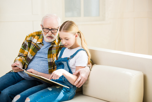 Grandfather with girl reading book - Foto, afbeelding
