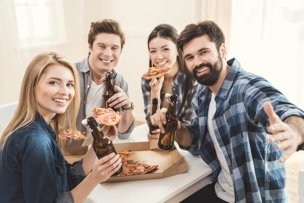 couples drinking beer and eating pizza - Фото, изображение