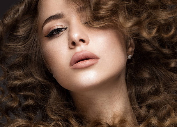 Beautiful brunette girl in move with a perfectly curly hair, and classic make-up. Beauty face. - 写真・画像