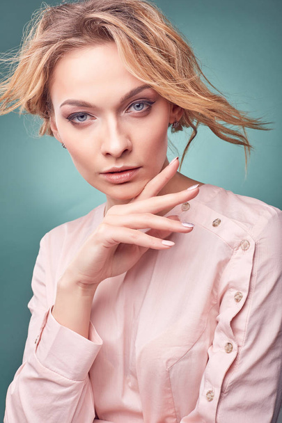 Portrait of young sexy romantic blonde woman, wearing light pink dress in studio with turquoise background - Fotó, kép