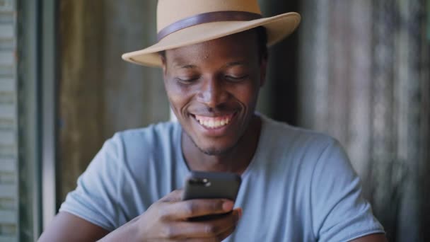 Fiatal, fekete ember ül egy modern, divatos kávézó - Felvétel, videó