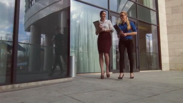 Positive businesswomen walking near office center - Video
