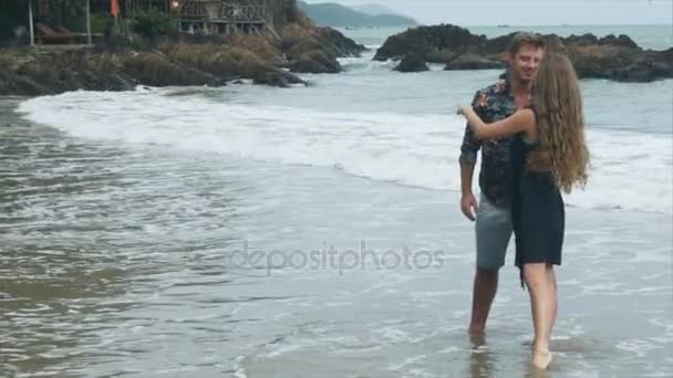 Hermosa pareja cariñosa besándose en la playa luego girando de la mano
 - Metraje, vídeo